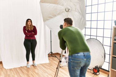 Fotoğraf stüdyosundaki genç kadın şüpheci ve gergin. Yüzünde çapraz kollu tasvip etmeyen bir ifade. negatif kişi. 