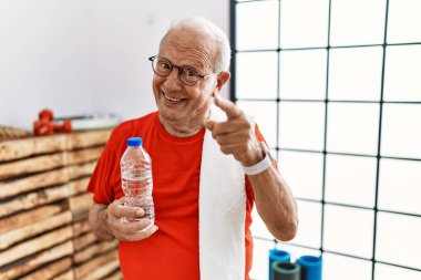 Spor kıyafetleri ve havlu giyen son sınıf öğrencisi mutlu ve komik yüzlü parmaklarını kameraya doğrultuyor. iyi enerji ve titreşimler. 