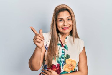 Orta yaşlı İspanyol kadın gündelik kıyafetler giyiyor. Gülümsüyor, mutlu bir şekilde elini ve parmağını yana uzatıyordu. 