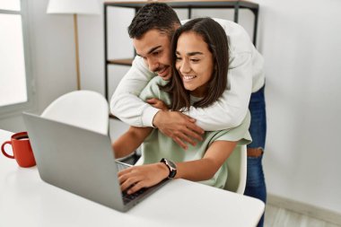 Laptop kullanan ve evde kahve içen genç bir çift..