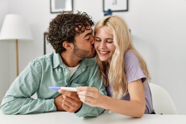 Mutlu genç çift evde hamilelik testine bakıyor.