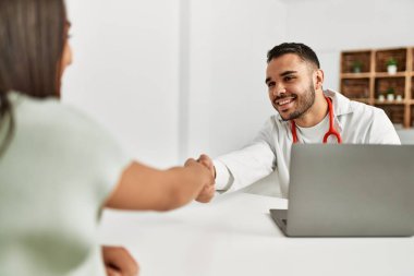 Klinikteki Latin kadın hastayla el sıkışan doktor..