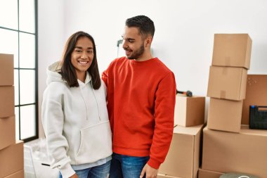 Genç Latin çift gülümsüyor mutlu bir şekilde yeni evinde duruyor.