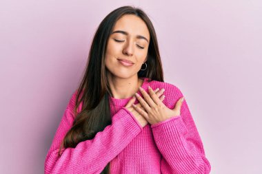 Elleri göğsünde gülümseyen, yüzünde minnet dolu bir jestle gülümseyen Latin asıllı genç bir kız. sağlık kavramı. 