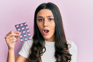 Genç İspanyol kadın elinde haplar tutuyordu. Korkmuş ve ağzı açık bir şekilde hayrete düşmüştü. 