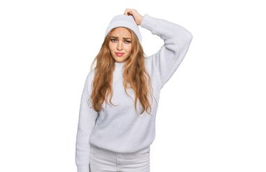 Genç beyaz kız yün kazak giyiyor ve kış şapkası takıyor. Soruyu merak ediyor. Şüpheyle kararsız, kafa kafaya düşünerek. Düşünceli kavram. 