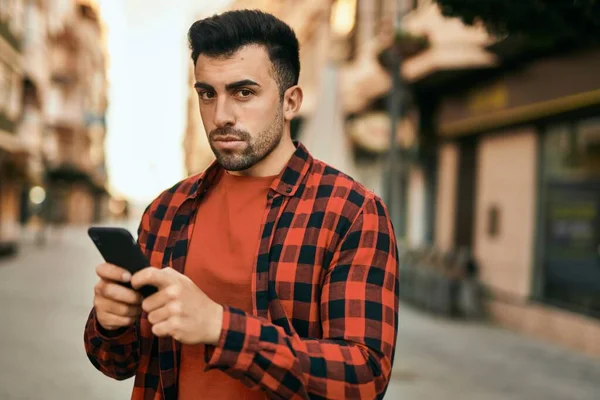 Joven Hombre Hispano Con Expresión Seria Usando Smartphone Ciudad —  Fotos de Stock
