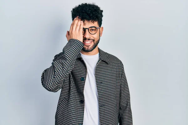 Sakallı genç Arap adam bir gözünü eliyle kapatıyor, yüzünde kendine güvenen bir gülümseme ve şaşırtıcı bir duygu var.. 