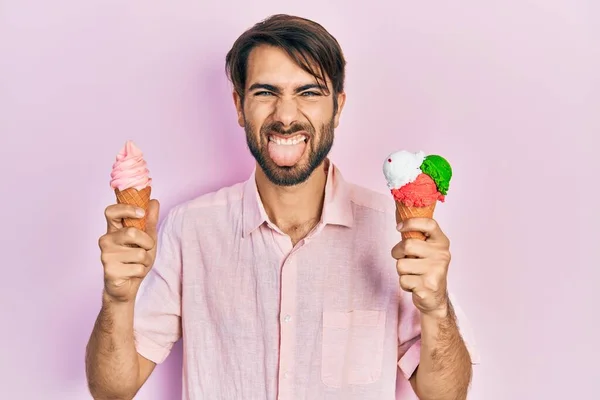 Young Hispanic Man Holding Ice Cream Sticking Tongue Out Happy — Stock Photo, Image