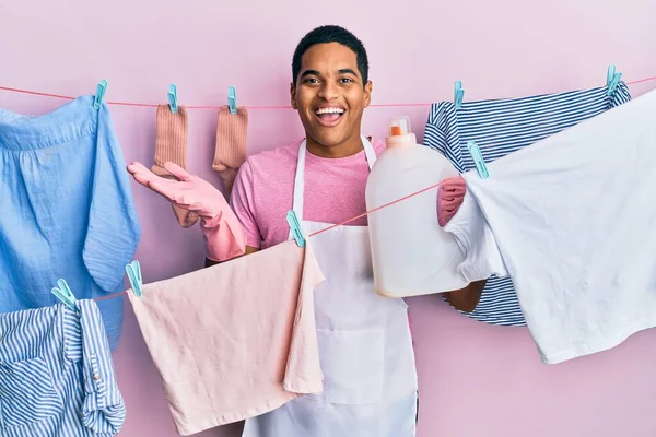 Jovem Homem Hispânico Bonito Fazendo Lavanderia Segurando Garrafa Detergente Celebrando — Fotografia de Stock