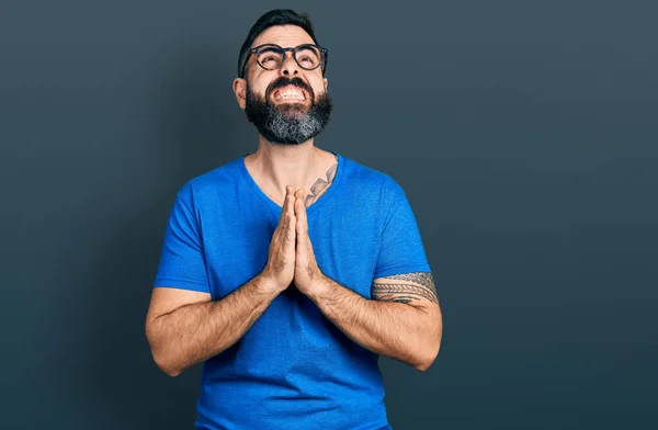 가벼운 티셔츠와 안경을 수염을 아메리카 남자가 희망의 표정으로 기도하는 감정적 — 스톡 사진