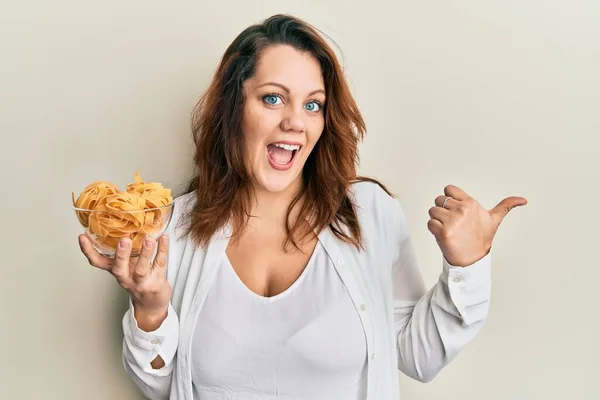 Joven Mujer Caucásica Sosteniendo Tazón Pasta Cruda Apuntando Con Pulgar —  Fotos de Stock