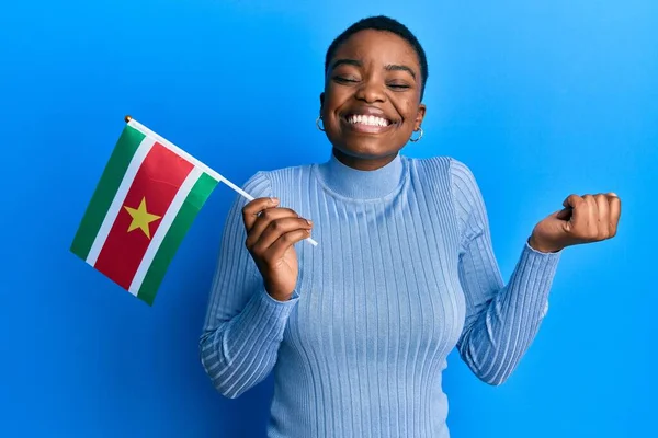 Young African American Woman Holding Suriname Flag Screaming Proud Celebrating — Stock Photo, Image