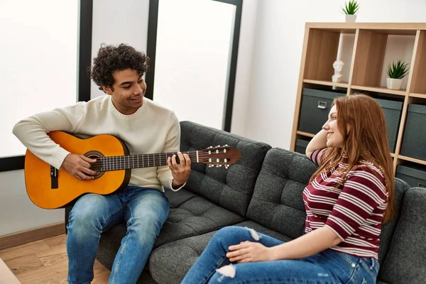 Jovem Casal Sorrindo Feliz Tocando Guitarra Clássica Sentado Sofá Casa — Fotografia de Stock