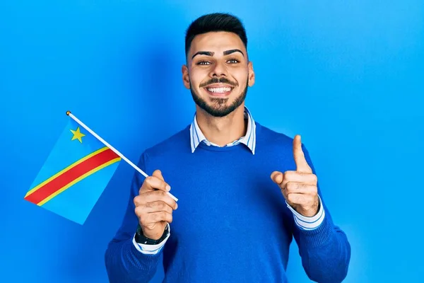 Joven Hispano Con Barba Sosteniendo República Democrática Bandera Congo Sonriendo —  Fotos de Stock