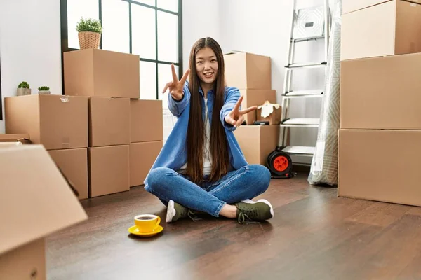 Joven Chica China Sentada Suelo Casa Nueva Sonriendo Mirando Cámara — Foto de Stock