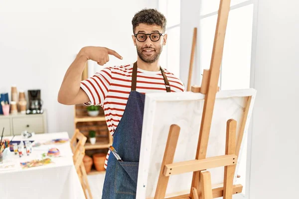 在艺术工作室里的阿拉伯年轻人看上去很自信 面带微笑 用手指指着自己 自豪而快乐 — 图库照片