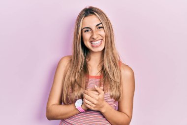 Güzel İspanyol kadın, günlük tişörtler giyip ellerini birleştiriyor ve gülümseyerek gevşemiş ve neşeli gülümsüyor. Başarı ve iyimserlik 