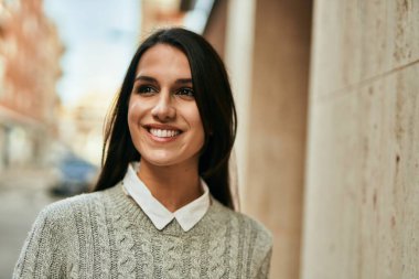 Genç İspanyol kadın gülümseyerek şehirde mutlu mesut dikiliyor..