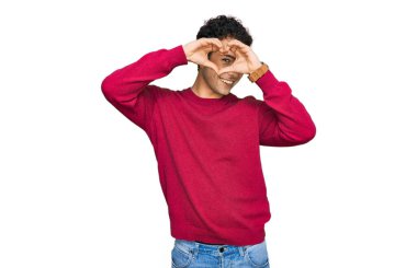 Gündelik giysiler giymiş, elleri ve parmaklarıyla kalp şeklinde gülümseyen genç yakışıklı adam tabeladan bakıyor. 