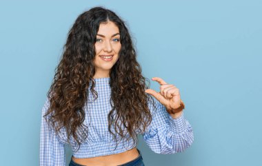 Gündelik kıyafetler giyen, gülümseyen, kendine güvenen, el hareketi yapan, parmaklarıyla işaret yapan ve kameraya bakan genç İspanyol kız. ölçüm kavramı. 