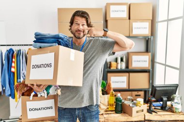 Gönüllü olarak bağış kutusunu tutan yakışıklı orta yaşlı bir adam el ele tutuşup gülümsüyor. güzellik konsepti 