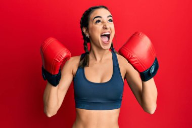 Genç esmer kız boks eldiveni kullanıyor. Kızgın ve kızgın çığlıklar atıyor. Öfkeyle bağırıyor.. 