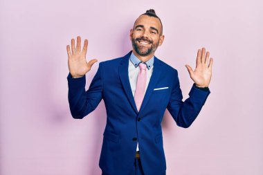 Genç İspanyol takım elbiseli ve kravatlı adam on numarayı gösterip işaret ederken kendinden emin ve mutlu gülümsüyor.. 