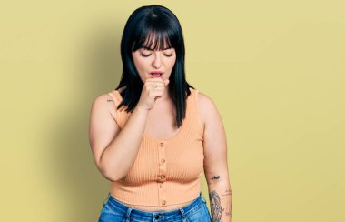 Latin kökenli genç ve iri bir kadın günlük kıyafetler giyip kendini iyi hissetmiyor ve soğuk algınlığı veya bronşitin belirtisi olarak öksürüyor. sağlık hizmeti kavramı. 