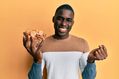 Genç Afro-Amerikan adam elinde tuzlu bisküvilerle haykırıyor gururla, zaferi kutluyor ve başarıyı kollarını kaldırarak kutluyor. 