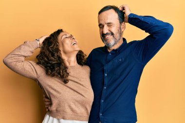 Orta yaşlı İspanyol çift gündelik kıyafetler giyip gülümsüyor saçlarına dokunuyor, el hareketi yapıyor, çekici ve modaya uygun poz veriyorlar. 