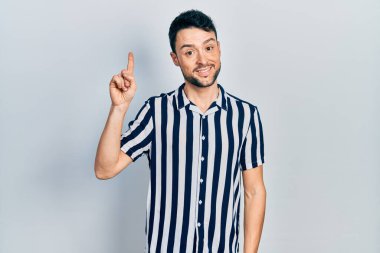 Gündelik kıyafetler giyen genç İspanyol bir numarayı gösterip işaret ederken kendinden emin ve mutlu bir şekilde gülümsüyor.. 