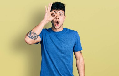 Sıradan tişörtler giyen genç İspanyol adam şaşırmış yüz ifadesiyle şaşırmış, parmaklarından içeri bakıyor. İnançsız ifade. 