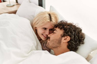 Genç, güzel bir çift yatakta uzanıyor ve evde battaniyeyle örtüyor..