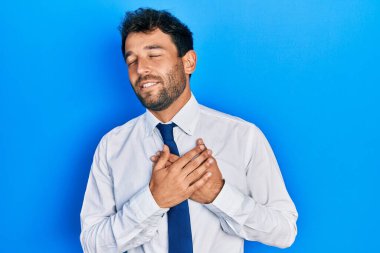 Sakallı, iş gömleği giyen ve kravat takan elleri göğsünde, gözleri kapalı, yüzünde minnet ifadesi olan yakışıklı bir adam. sağlık kavramı. 