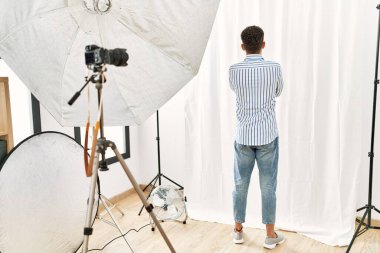 Fotoğraf stüdyosunda model gibi davranan Arap genç adam arkasını dönüp kollarını kavuşturarak diğer tarafa bakıyordu. 