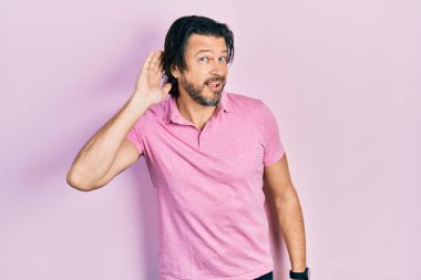 Orta yaşlı beyaz tişörtlü bir beyaz adam kulağından girip kulağına fısıldayarak dedikodu ve dedikoduları dinliyor. Sağırlık kavramı. 