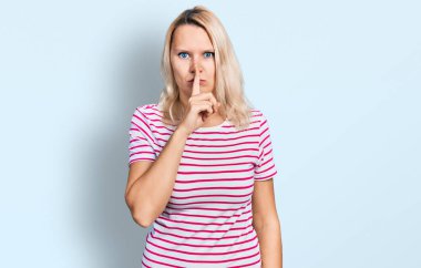 Gündelik giysiler giyen genç beyaz kadın sessiz olmak istiyor dudakları parmaklarla. sessizlik ve gizli konsept. 