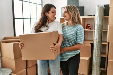 Genç ve güzel bir çift mutlu bir şekilde gülümsüyor. Yeni evlerinde karton kutu tutuyorlar..