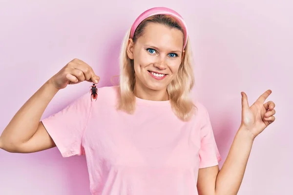 Beautiful Caucasian Blonde Woman Holding Cockroach Smiling Happy Pointing Hand — ストック写真