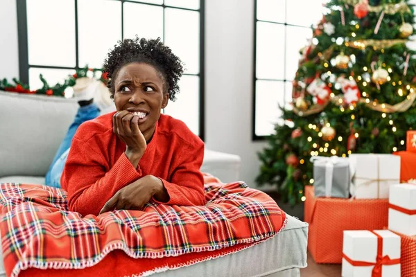 Młoda Afroamerykanka Leżąca Kanapie Obok Choinki Wyglądająca Zestresowaną Zdenerwowaną Rękami — Zdjęcie stockowe