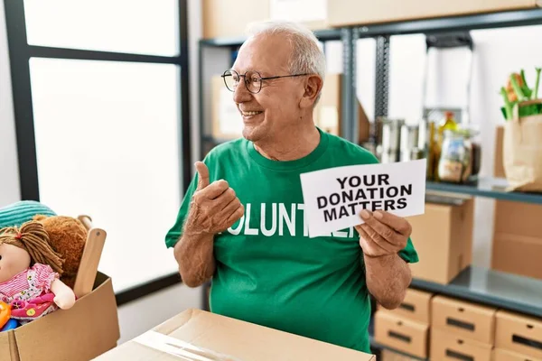 Senior Vrijwilliger Houdt Donatie Zaken Wijzen Duim Naar Zijkant Glimlachend — Stockfoto