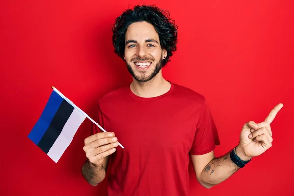Bonito Hispânico Segurando Bandeira Estonia Sorrindo Feliz Apontando Com Mão — Fotografia de Stock