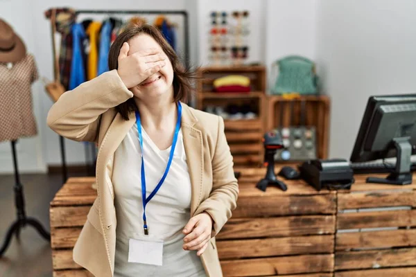 小売店の店長として働いている若いダウン症候群の女性は笑顔で 驚きのために目をカバー顔に手で笑っています 視覚障害の概念 — ストック写真