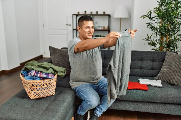 年轻的惊慌失措的男人在家里高兴地折叠着衣服 — 图库照片