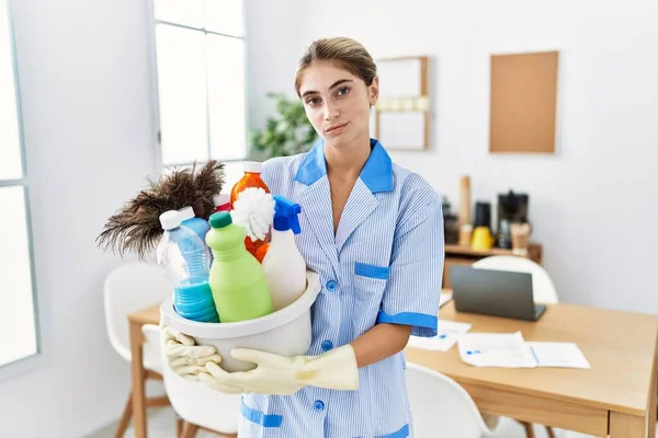 Junge Blonde Frau Sauberer Uniform Hält Putzmittel Entspannt Mit Ernstem — Stockfoto