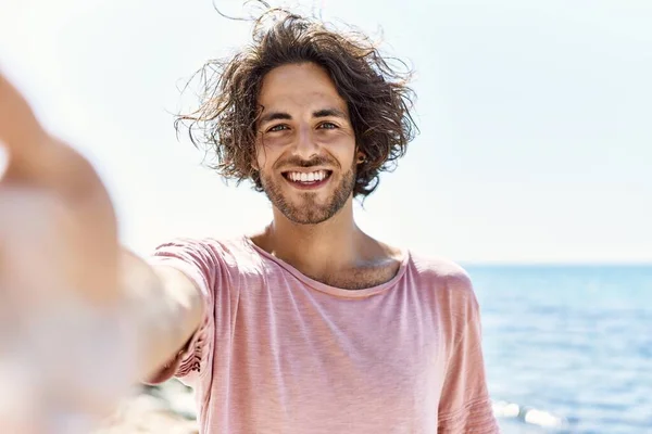 年轻的他惊慌失措的人高兴地微笑着 站在海滩上的摄像机前自投罗网 — 图库照片