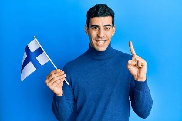 Hombre Hispano Guapo Sosteniendo Bandera Finlandia Sonriendo Con Una Idea —  Fotos de Stock