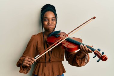 Saçları örgülü, keman çalan komik yüzlü Afrikalı Amerikalı kadın. Ağzı havayla şişer, havayı yakalar.. 