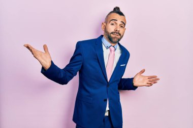 Genç İspanyol takım elbiseli, kravatlı, aptal ve elleri havada, kafası karışmış bir adam. şüphe kavramı. 